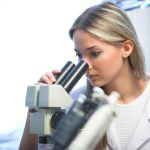 beauty researcher looking through microscope in laboratory